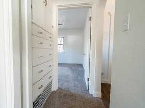 Hall with dark carpet and a textured wall