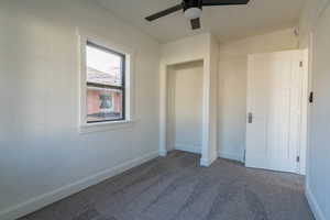 Unfurnished bedroom featuring dark colored carpet and ceiling fan