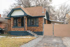 View of front of home featuring roof with shingles, a gate, and brick siding