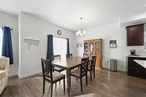 Dining area featuring dark wood-style flooring and a chandelier