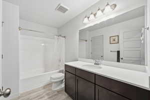 Bathroom featuring vanity, shower / bath combo with shower curtain, and light wood-style floors