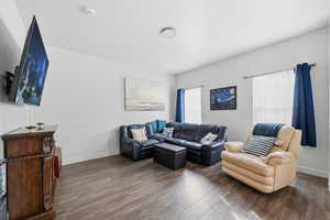 Living room featuring dark wood finished floors and baseboards