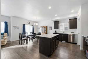 Kitchen with dark wood-style flooring, stainless steel appliances, hanging light fixtures, a center island, and a chandelier
