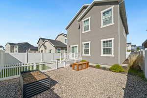 Back of house featuring a vegetable garden, a fenced backyard, stucco siding, and a residential view