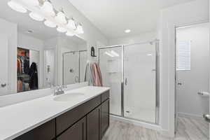 Bathroom with vanity, a stall shower, a spacious closet, and light wood-style flooring