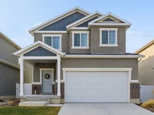 Craftsman-style home with board and batten siding, a garage, driveway, and brick siding