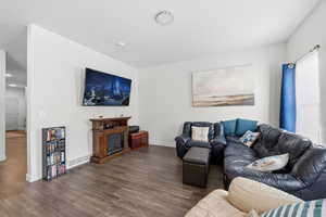 Living area featuring dark wood-type flooring and baseboards