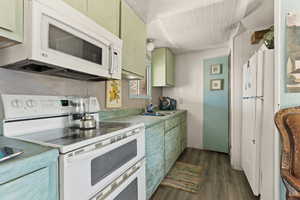 Kitchen featuring white appliances, light countertops, dark wood-style flooring, and green cabinetry