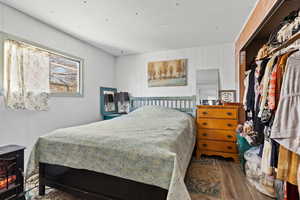 Bedroom with wood finished floors, a wood stove, wood walls, and a closet