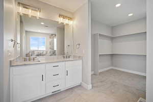 Bathroom featuring double vanity, recessed lighting, and light marble finish flooring