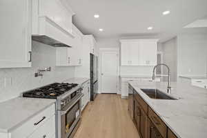 Kitchen featuring stainless steel appliances, light stone counters, white cabinetry, and recessed lighting