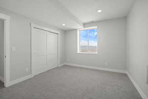 Unfurnished bedroom with light carpet, a closet, recessed lighting, and a textured ceiling