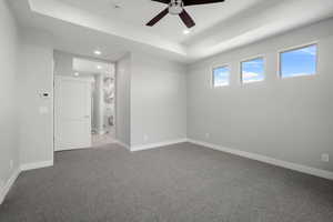 Empty room featuring a tray ceiling, ceiling fan, carpet, and recessed lighting