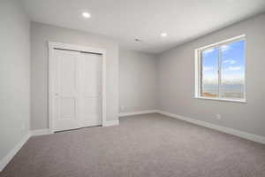 Unfurnished bedroom featuring light colored carpet, a closet, and recessed lighting