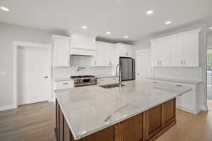 Kitchen featuring white cabinets, stainless steel appliances, decorative backsplash, brown cabinets, and recessed lighting