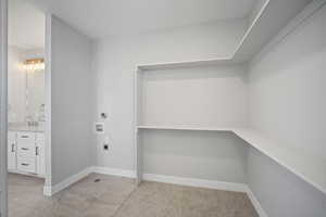 Washroom with hookup for an electric dryer, washer hookup, and light colored carpet