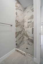 Full bath featuring a marble finish shower and marble finish floors