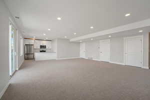 Unfurnished living room featuring light colored carpet and recessed lighting