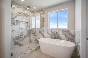 Bathroom featuring a marble finish shower, recessed lighting, a freestanding bath, and tile walls