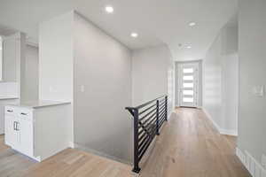 Staircase with wood finished floors and recessed lighting
