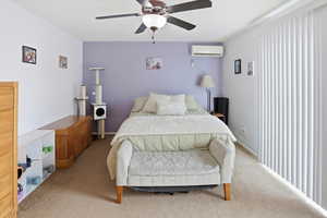 Bedroom featuring carpet flooring, a wall mounted AC, and ceiling fan