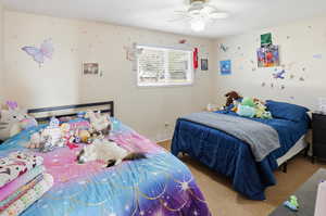 Carpeted bedroom with a ceiling fan