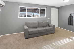 Living room with carpet floors and a wall unit AC