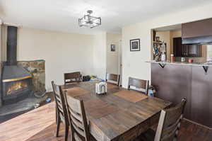 Dining space with dark wood finished floors, a wood stove, and a chandelier