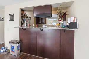 Kitchen featuring a kitchen breakfast bar, light stone countertops, and ventilation hood