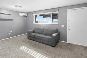 Living room with carpet flooring and a wall mounted AC