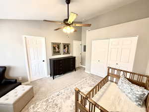 Carpeted bedroom featuring lofted ceiling, a closet, and ceiling fan