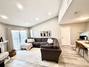 Living room featuring light wood-style flooring, recessed lighting, and high vaulted ceiling