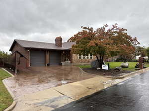 View of front facade with a chimney, a front lawn, brick siding, an attached garage, and decorative driveway