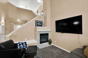 Carpeted living room featuring a tiled fireplace and baseboards