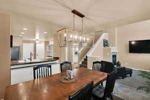 Dining space with a chandelier, recessed lighting, a glass covered fireplace, and stairs
