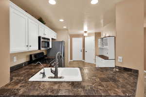 Kitchen featuring white cabinets, dark countertops, stainless steel appliances, and recessed lighting