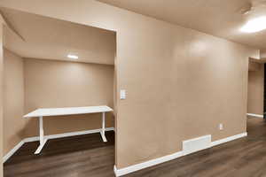 Hallway with dark wood-type flooring, a textured ceiling, and a textured wall