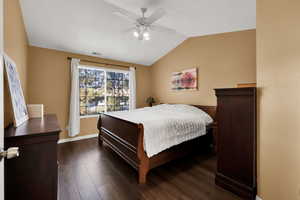 Bedroom featuring vaulted ceiling, dark wood-type flooring, and ceiling fan
