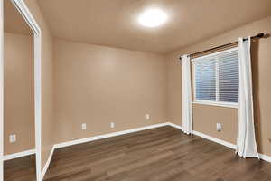 Empty room featuring a textured ceiling and dark wood-style flooring