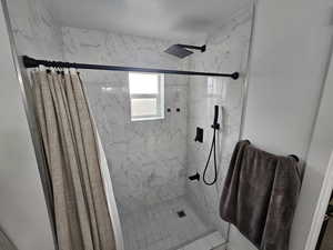Full bath with a marble finish shower