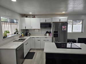 Kitchen featuring stainless steel appliances, light stone countertops, recessed lighting, light wood-style floors, and white cabinets