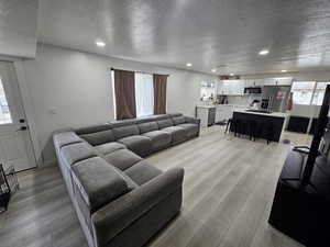 Living area with a textured ceiling, recessed lighting, and light wood-style flooring
