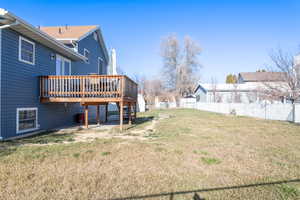 View of east side of the house with newer siding, deck, and a large yard.
