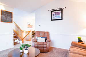 Carpeted living area with baseboards, chair rail trim, vaulted ceiling, and amazing picture window to watch the sunset.