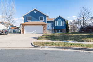 View of front of house with newer siding, concrete driveway, and a 2 car garage with a large yard. Space for rv parking.