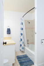 Full bathroom featuring shower / tub combo with curtain, vanity, and light tile patterned floors.