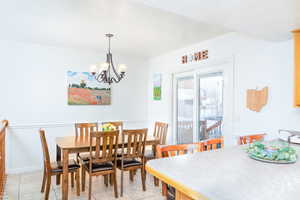 Dining room featuring a chandelier and light tile patterned floors, and chair rail trim.
