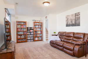 Large family room with carpet, and brick wall for a fireplace.