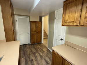 Basement office with built in desk and dark wood-style floors, oak cabinets, and above grade window.