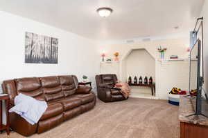Large family room with carpet, and brick wall for a fireplace.